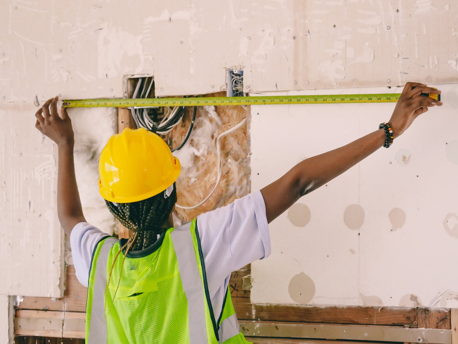 a construction worker measuring a wall with a tape measure