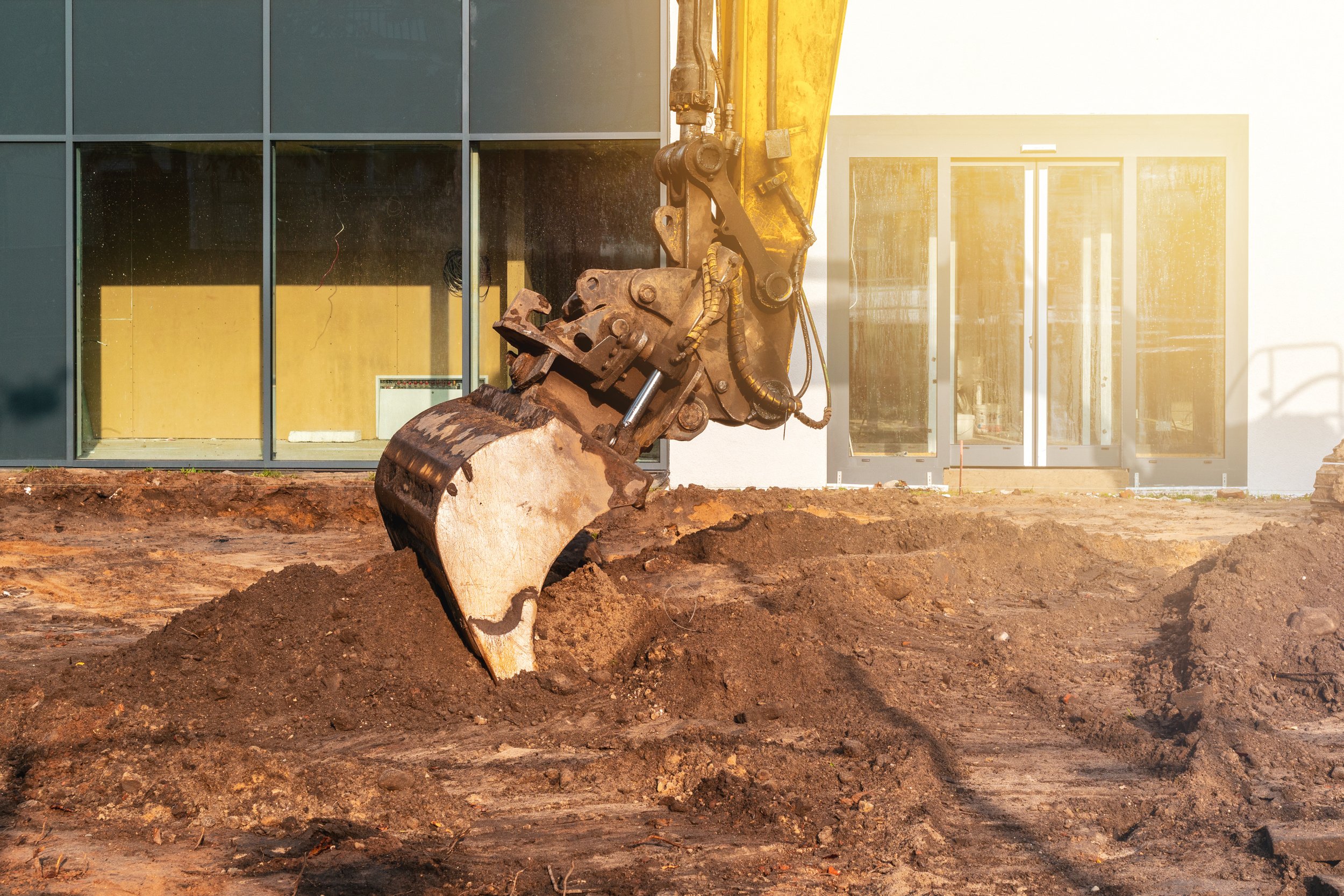 an excavator digging dirt in front of a building