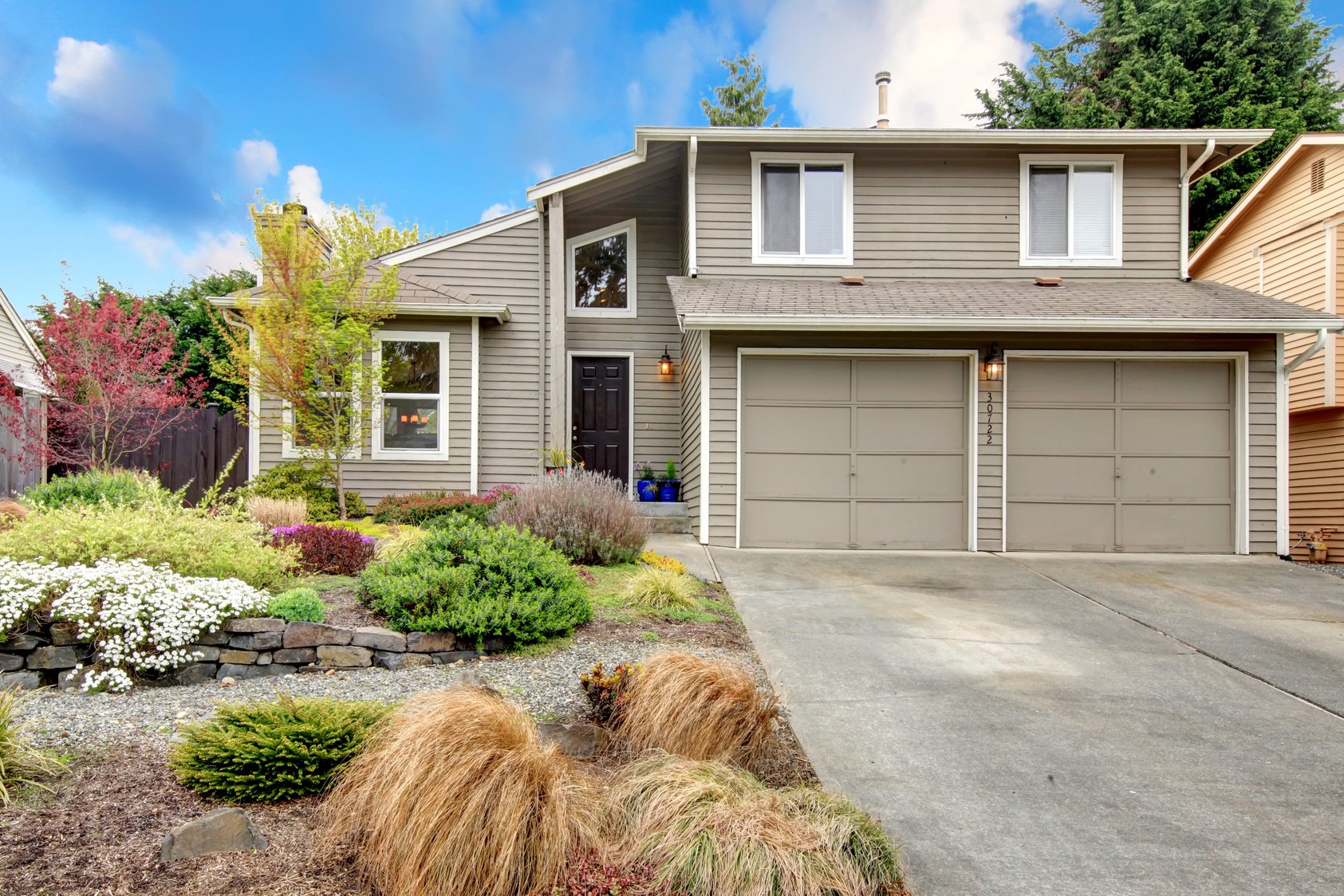 a home with two garages and landscaping in the front yard